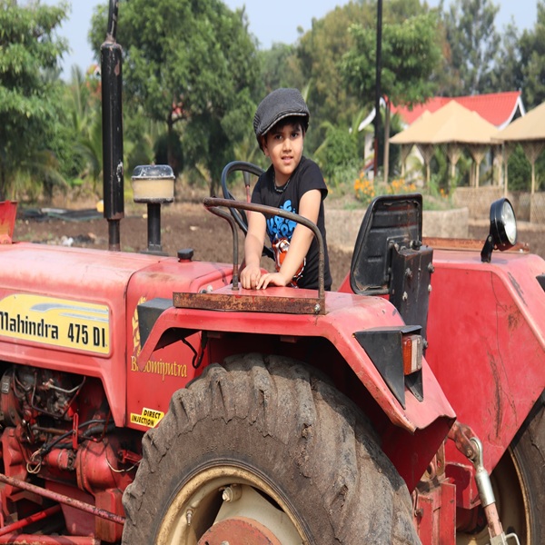 Child enjoying a tractor ride at Agatya Agro Tourism, the best resort in Shirdi.